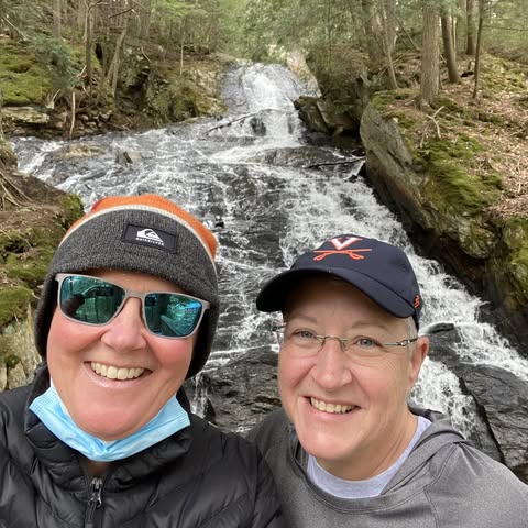 Two friends smiling by a waterfall.