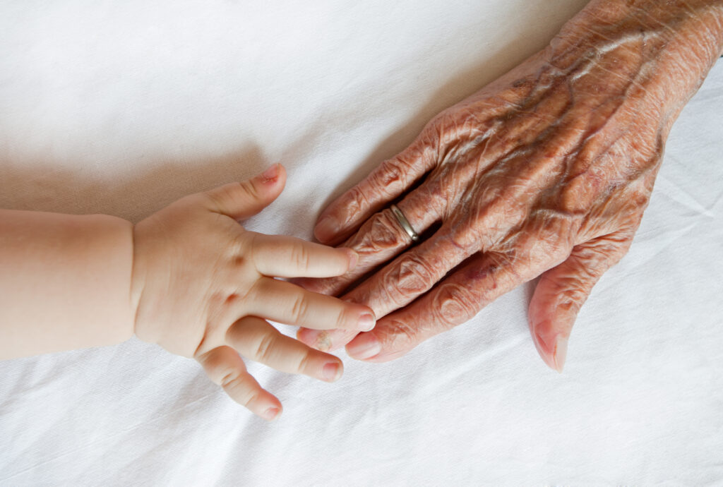 Intergenerational hands on a white fabric.